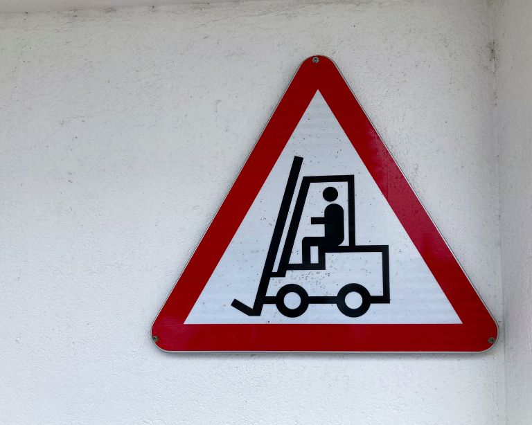 Imagen de una señales de advertencia ante el paso de carretillas elevadoras para advertir en el interior de naves industriales o almacenes industriales. 